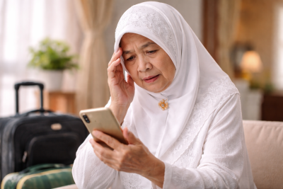 Illustrasi wanita lansia Indonesia sedang menatap layar ponselnya. Kebijakan war tiket dinilai akan merugikan pihak yang sulit mengakses internet, termasuk lansia.